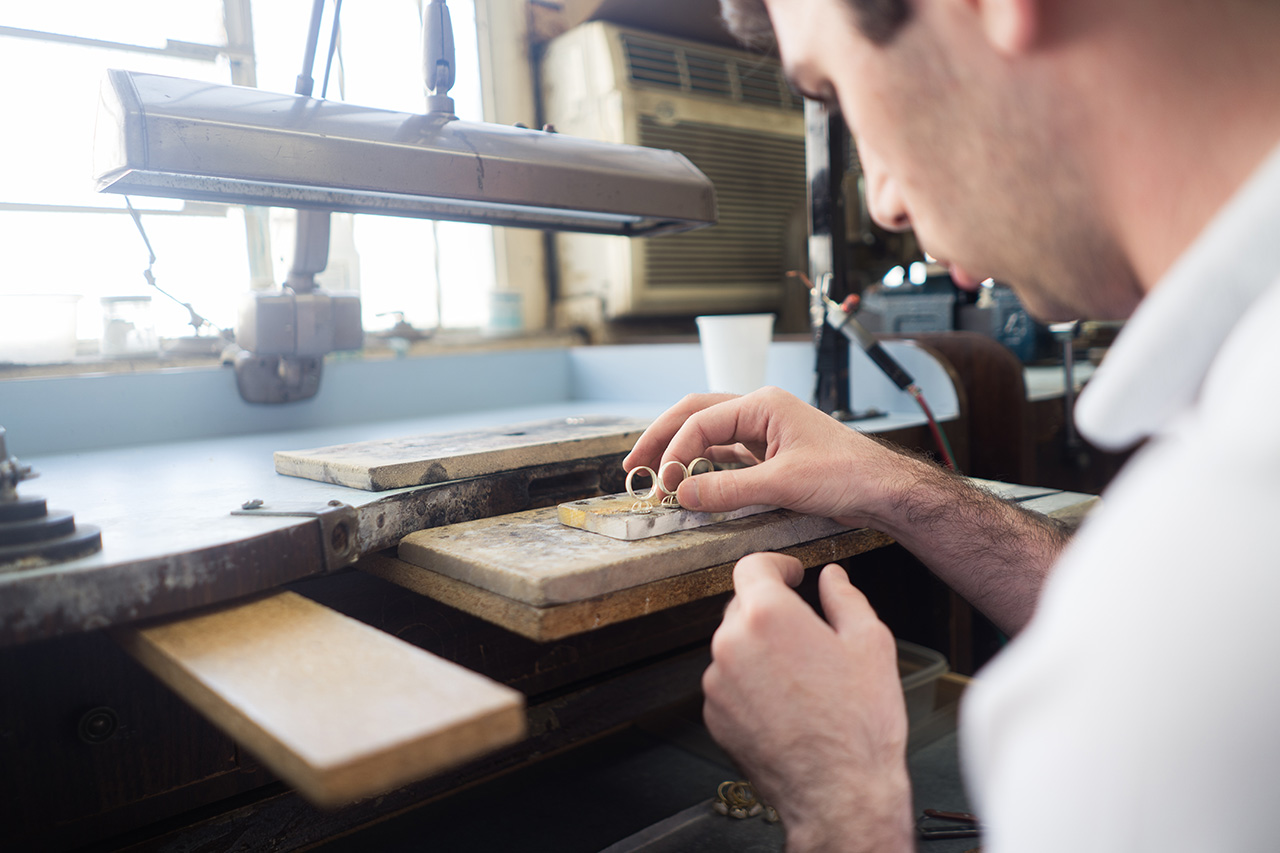 Overseas shipping containers contrasted with jewelry designer inspecting prototype in Los Angeles