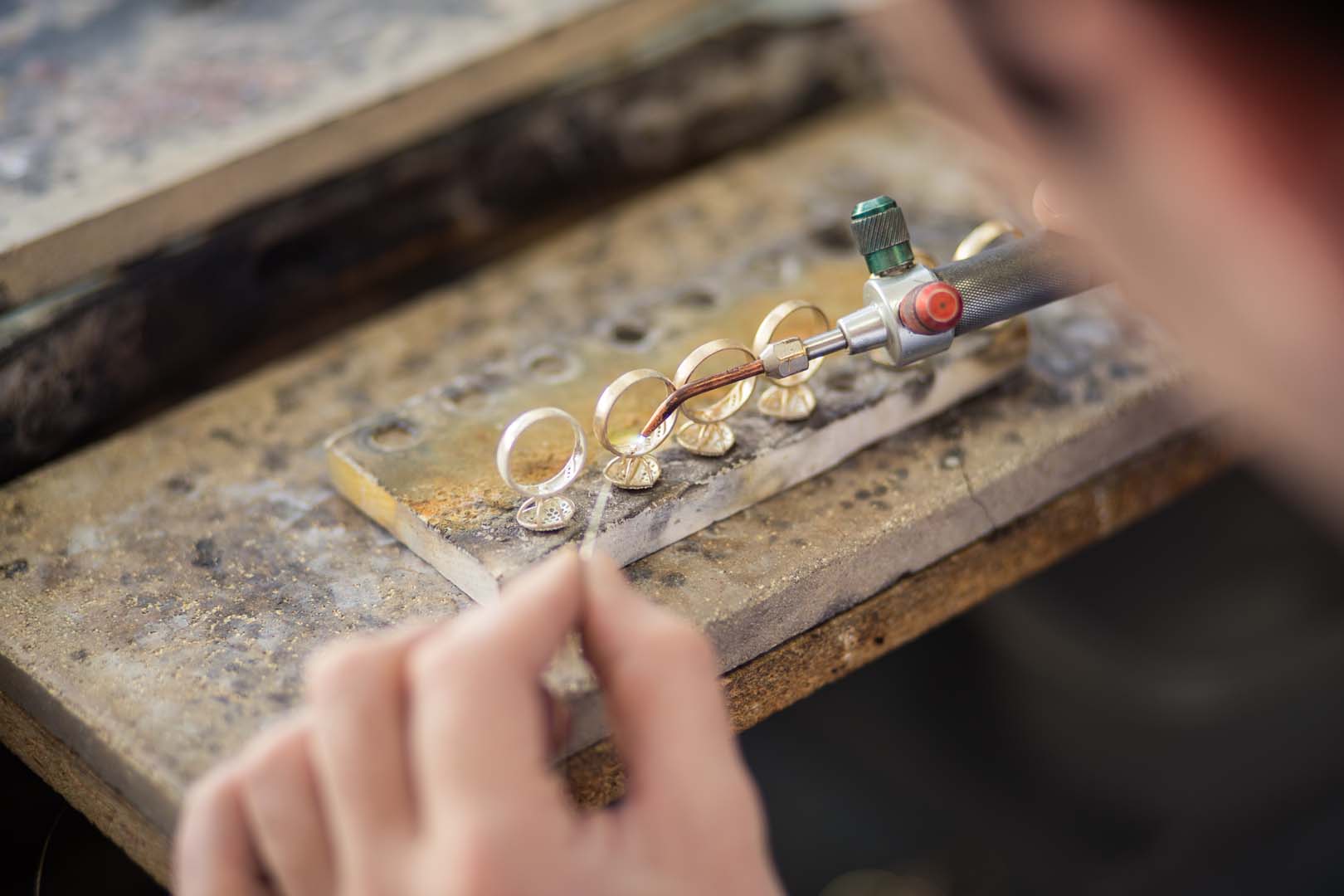 Gemstones, design blueprints, and jewelry samples illustrating custom manufacturing decisions